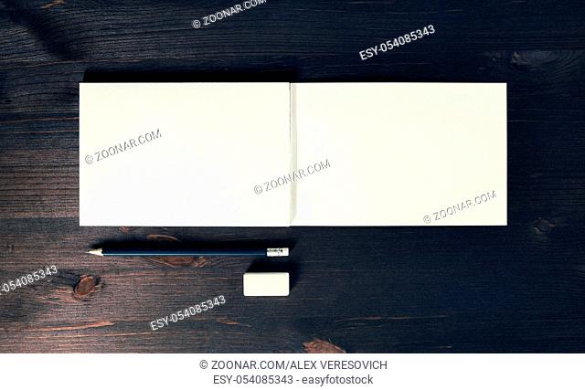 Photo of open sketchbook with blank pages, pencil and eraser on wooden background. Responsive design template. Flat lay