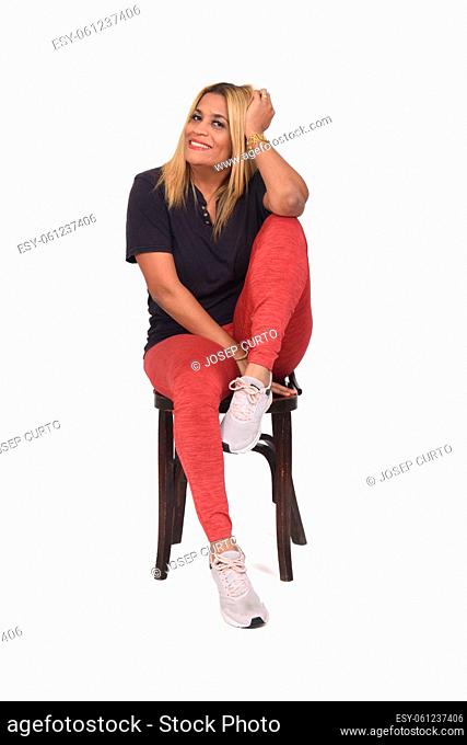 woman dressed in sportswear sitting on a chair with her foot on top of the chair on white background