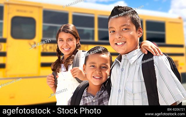 Young hispanic boys and girl walking near school bus