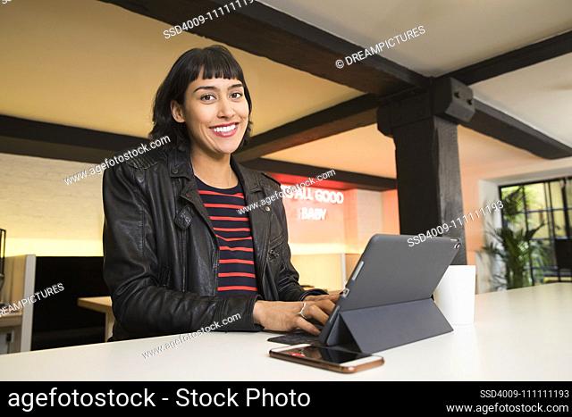 woman sitting at counter working on tablet in co-working space