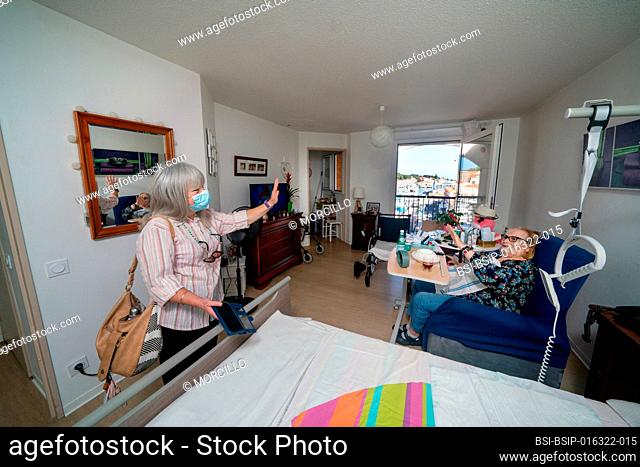 Caregiver in a retirement home looking after a septuagenarian with Parkinson's to do her cooking and cleaning