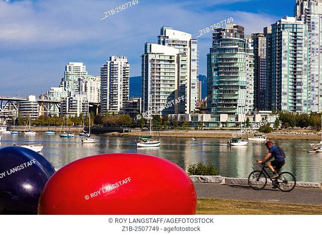 Cyclist riding by a jellybean art installation in False Creek, Vancouver