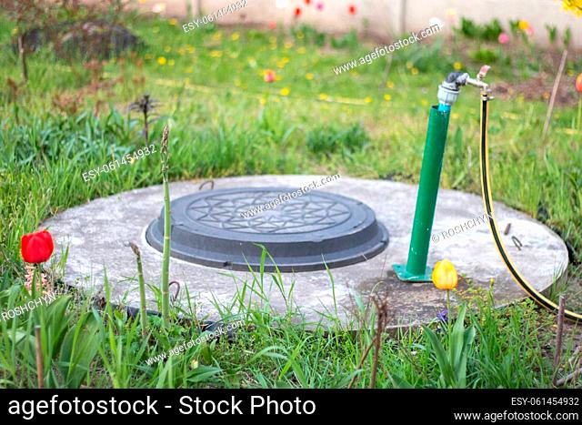 Plumbing, water pump from a well. An outside water faucet with a yellow garden hose attached to it. Irrigation water pumping system for agriculture