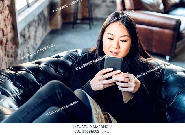 Woman on armchair using smartphone