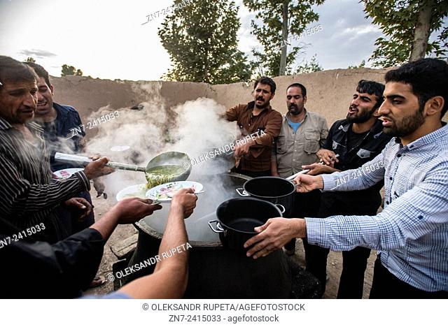 Men serves ritual lunch soup with beans, threads and vegetables for participants of rehearsal of Tazieh, ritual theater of the day of Ashura