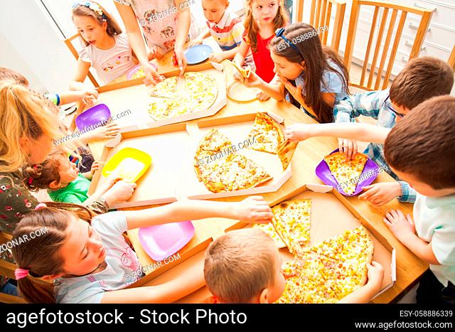 Happy kids eating pizza and having fun together. Birthday party