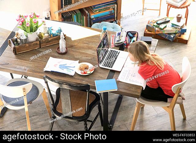 Girl studying over laptop on dining table at home