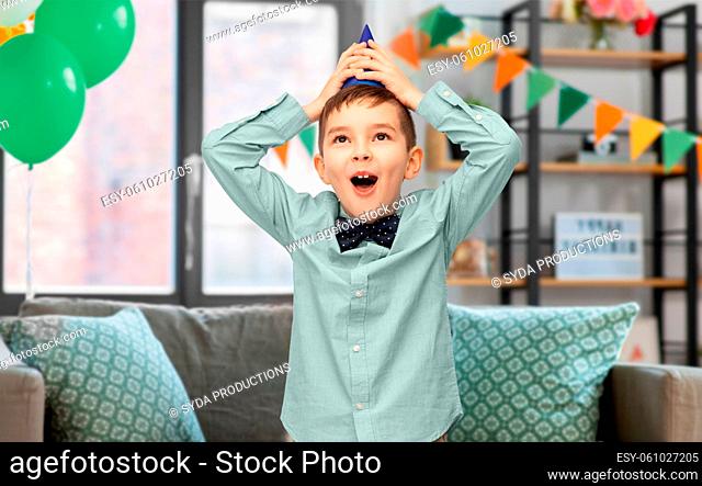 happy little boy holding to his birthday party hat