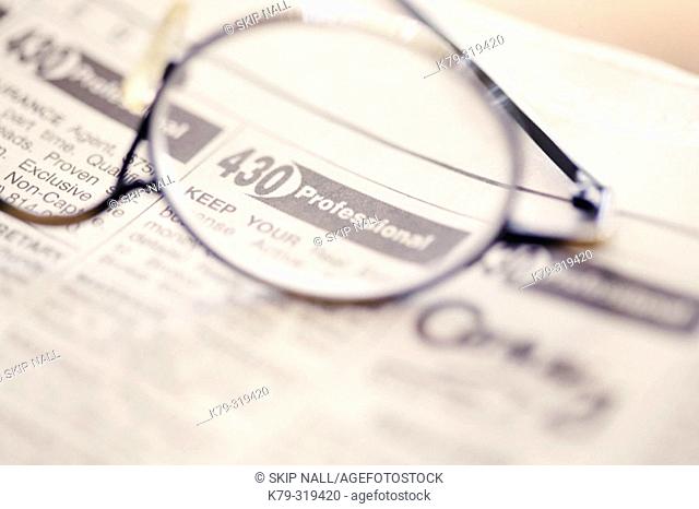 Glasses laying on classified ads