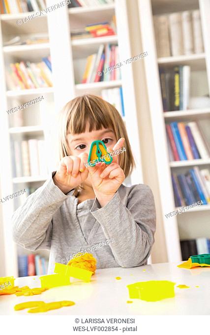 Little girl cutting out yellow modeling clay