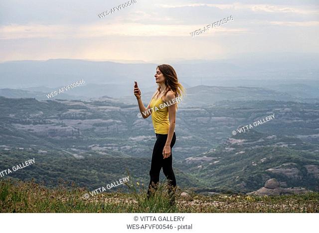 Spain, Barcelona, young woman taking selfie on Montcau Mountain