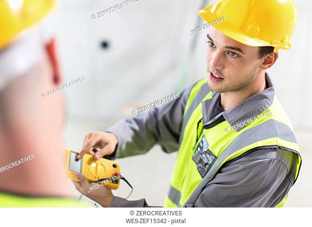 Electricians working with voltmeter on construction site
