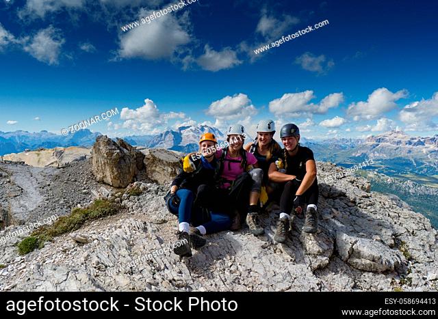 four attractive women mountain climbers hug and smile on a mountain peak after a hard climb in the Italian Dolomites near Cortina d'Ampezzo