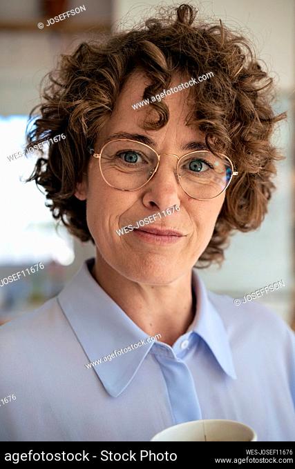 Smiling businesswoman with brown curly hair wearing eyeglasses