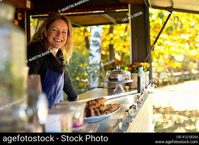 Portrait happy female food cart owner working in park
