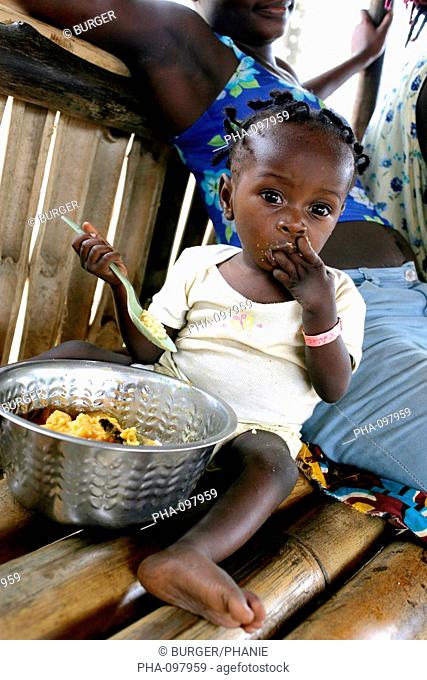Child suffering from malnutrition tasting a rice-based ordinary meal. Therapeutic Feeding Center in Monrovia, Liberia, implemented by Action contre la Faim ACF