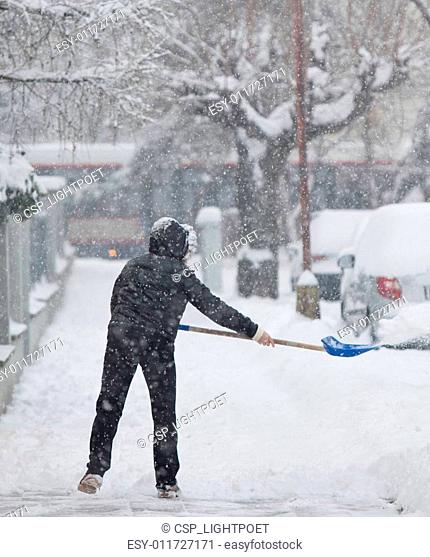 Woman shoveling snow from a sidewalk