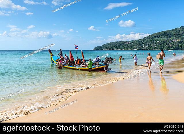 Phuket, Thailand People ride a long tail boat and relax on the Karon beach in Phuket, Thailand