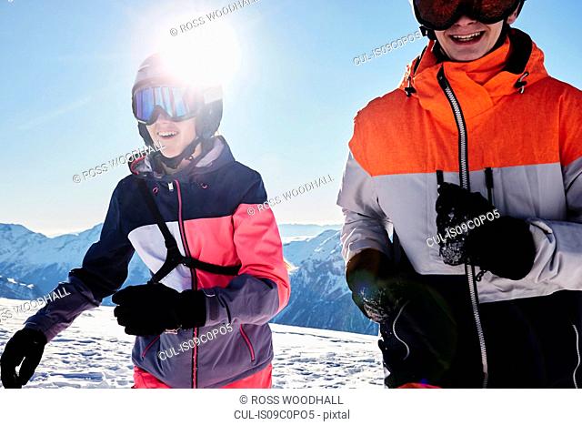 Teenage brother and sister skiers on snow covered mountain top, Alpe-d'Huez, Rhone-Alpes, France