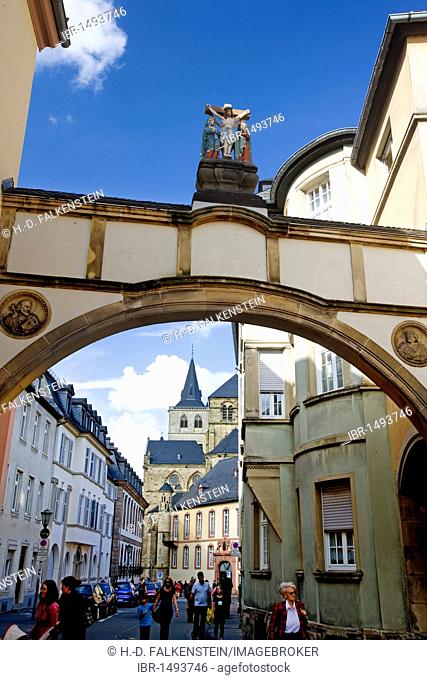 Crucifixion sculpture on an archway, Church of Our Lady, Liebfrauenkirche, and the Cathedral of Trier, Trierer Dom, at the back, Trier, Rhineland-Palatinate