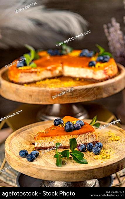 Slice of tasty cheesecake with salted caramel sauce on top decorated with blueberry