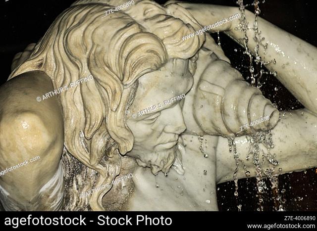 Detail, one of two fountain tritons. Amenano Fountain, night view. Piazza Duomo, Metropolitan City of Catania, Sicily, Italy