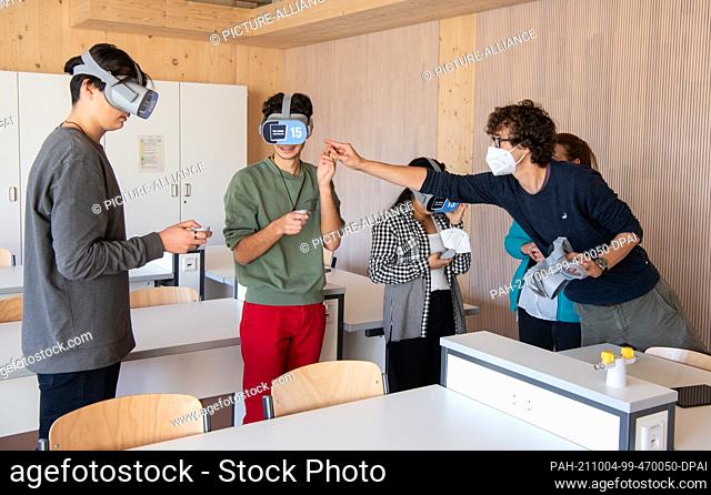 01 October 2021, Hessen, Frankfurt/Main: Teacher Hannes Pulch explains to students at the Adorno-Gymnasium in Frankfurt the function of VR glasses