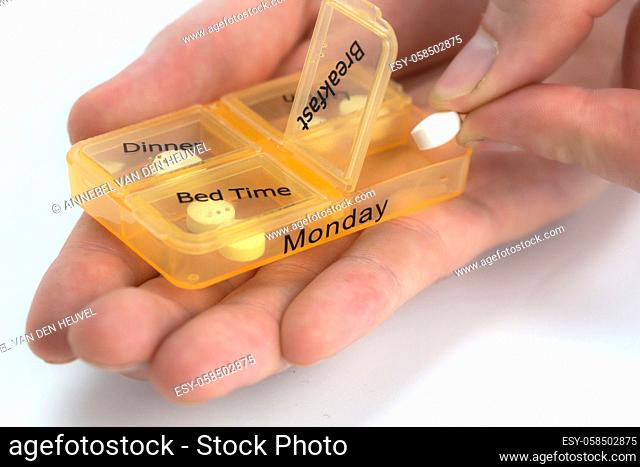 Hands of human with pill reminder box, taking medication isolated on white background, pill organizer box for monday copy space