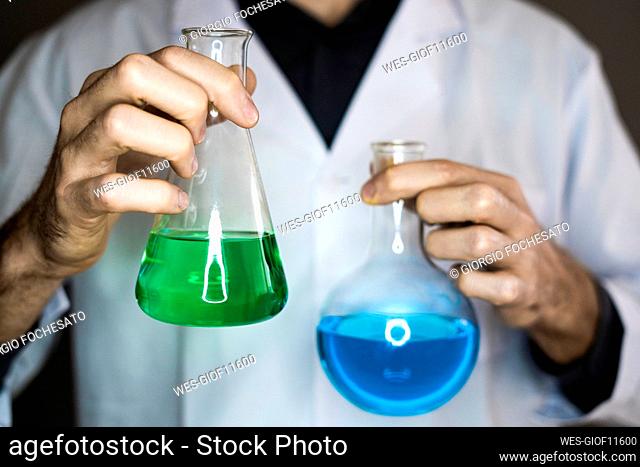 Scientist holding flasks with liquids in laboratory