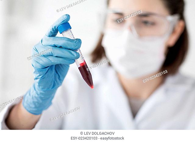 science, chemistry, biology, medicine and people concept - close up of young female scientist holding tube with blood sample making and test or research in...