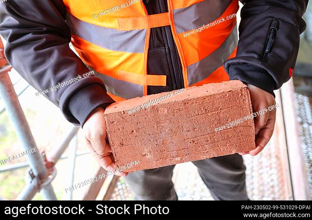 02 May 2023, Saxony, Jocketa: Construction manager Seweryn Fic holds a new brick for the more than 150-year-old Elstertal Bridge in the Vogtland region