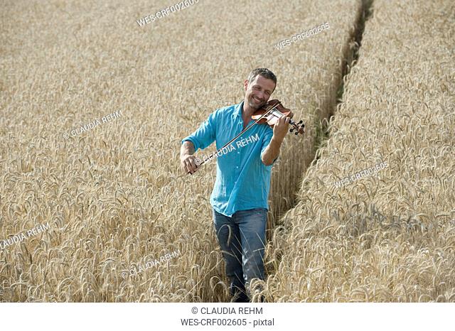 Germany, Bavaria, Starnberg Region, Man playing violin in field