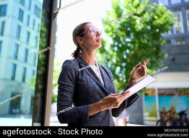 Businesswoman looking up and gesturing holding tablet PC