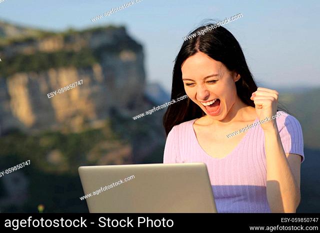 Excited asian woman celebrating checking laptop