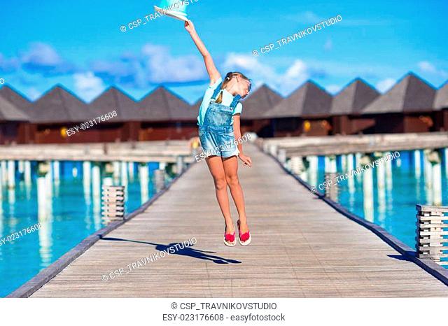 Adorable little girl having fun on wooden jetty near water bungalow