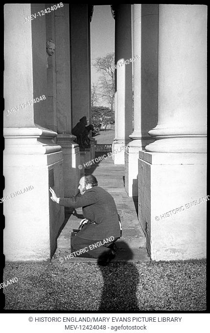 A detailed image of Neville Whittaker, an architect and co-writer of Historic Architecture of Durham with Ursula Clark, seen kneeling in the portico of Wynyard...