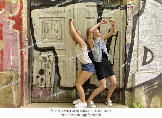 Two women dancing in door frame, graffiti, in Munich, Germany