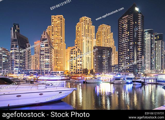Dubai Marina Port, UAE, United Arab Emirates - Jetty With Many Moored Yachts In Evening Night Illuminations. Night View Of Dubai Marina Towers