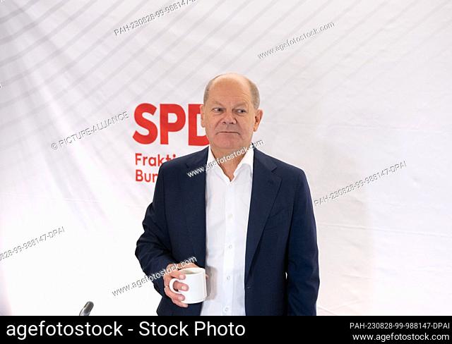 28 August 2023, Hesse, Wiesbaden: Chancellor Olaf Scholz (SPD) arrives at the closed meeting of the SPD parliamentary group in Wiesbaden with a coffee cup in...