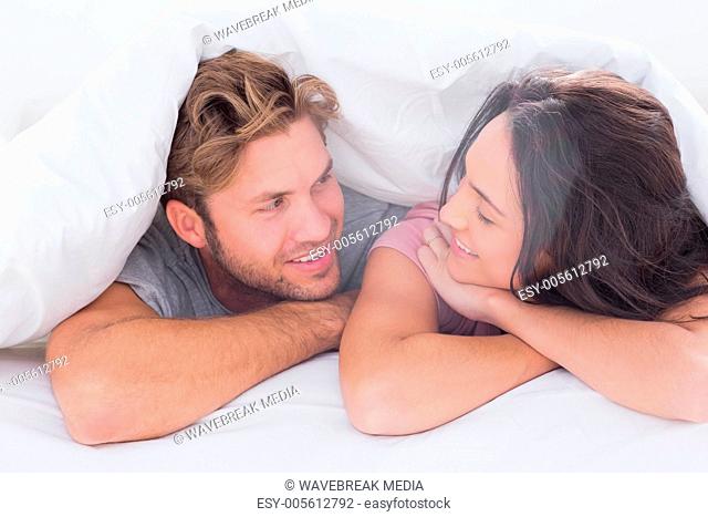 Couple under quilt smiling