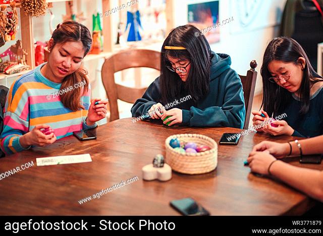 Young women decorating the Easter eggs by scratching patterns on dyed eggs. Traditional Easter time, spring time, new beginnings