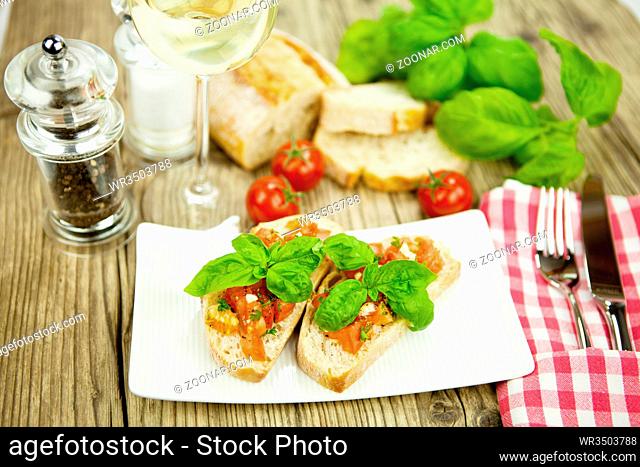 frische italienische Bruschetta mit Tomaten und Knoblauch auf einem Teller auf einem Holztisch