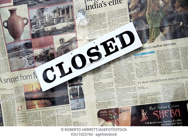 Closed sign and newspaper in shop window