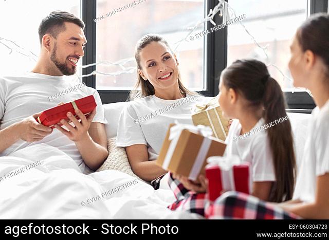 happy family with christmas gifts in bed at home