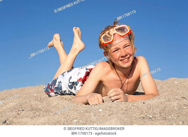 Young boy with diving goggles lying on the beach, Timmendorf, Poel island, Mecklenburg-Western Pomerania, Northern Germany