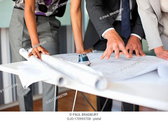 Architects looking at blueprints in office