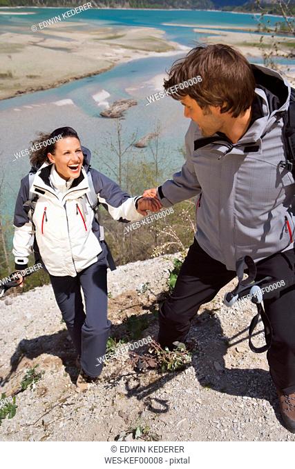 Germany, Bavaria, Couple trekking, man helping woman