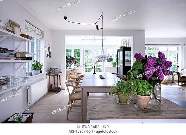 Bright, friendly and cozy, Scandinavia. An airy kitchen with white walls and unit doors. An island with flowers