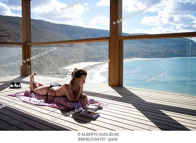 Caucasian woman sunbathing on deck over beach