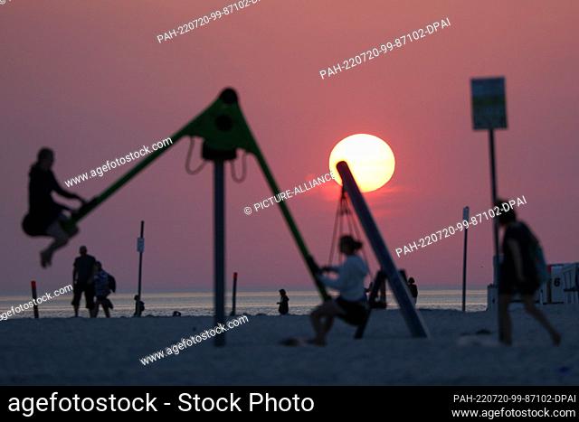 19 July 2022, Schleswig-Holstein, St. Peter Ording: Visitors are on the beach in St. Peter-Ording in the evening at sunset and summer temperatures